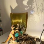 Toy dinosaur and forest figures cast large shadows on a wall in a classroom light-table display.